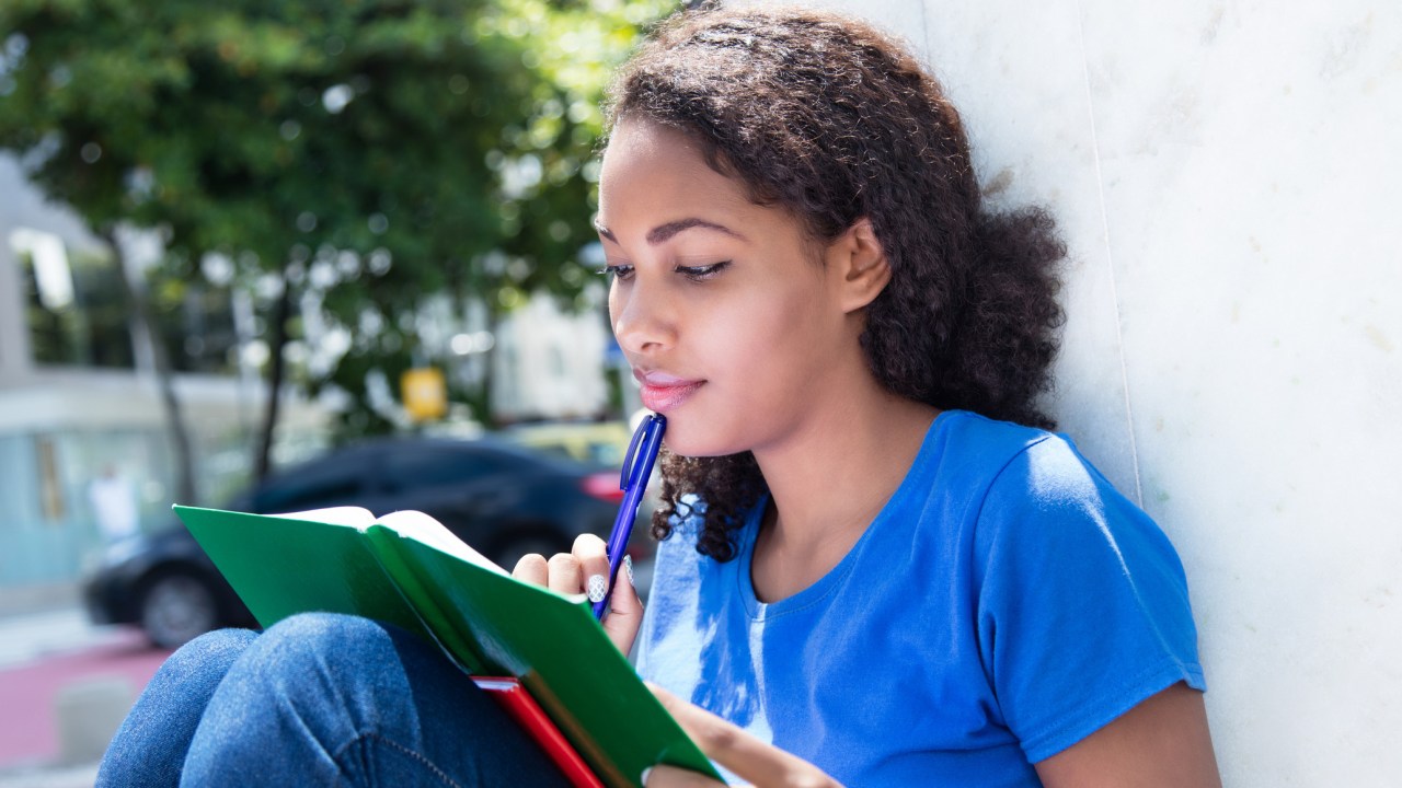 menina olhando para o caderno de estudos