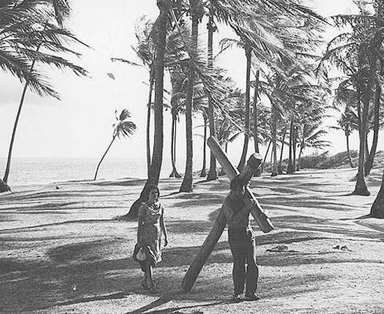 O Pagador de Promessas (1962), dirigido por Anselmo Duarte, é baseado no livro homônimo de Dias Gomes. Zé do Burro (Leonardo Villar) e sua mulher Rosa (Glória Menezes) vivem em uma pequena propriedade a 42 quilômetros de Salvador. Um dia, o burro de estimação de Zé é atingido por um raio e ele acaba indo a um terreiro de candomblé, onde faz uma promessa a Santa Bárbara para salvar o animal. Com o restabelecimento do bicho, Zé põe-se a cumprir a promessa e doa metade de seu sítio, para depois começar uma caminhada rumo a Salvador, carregando nas costas uma imensa cruz de madeira. Mas a via crucis de Zé ainda se torna mais angustiante ao ver sua mulher se engraçar com o cafetão Bonitão (Geraldo Del Rey) e ao encontrar a resistência ferrenha do padre Olavo (Dionísio Azevedo) a negar-lhe a entrada em sua igreja, pela razão de Zé haver feito sua promessa em um terreiro de macumba. O Pagador de Promessas (1962), dirigido por Anselmo Duarte, é baseado no livro homônimo de Dias Gomes. Zé do Burro (Leonardo Villar) e sua mulher Rosa (Glória Menezes) vivem em uma pequena propriedade a 42 quilômetros de Salvador. Um dia, o burro de estimação de Zé é atingido por um raio e ele acaba indo a um terreiro de candomblé, onde faz uma promessa a Santa Bárbara para salvar o animal. Com o restabelecimento do bicho, Zé põe-se a cumprir a promessa e doa metade de seu sítio, para depois começar uma caminhada rumo a Salvador, carregando nas costas uma imensa cruz de madeira. Mas a via crucis de Zé ainda se torna mais angustiante ao ver sua mulher se engraçar com o cafetão Bonitão (Geraldo Del Rey) e ao encontrar a resistência ferrenha do padre Olavo (Dionísio Azevedo) a negar-lhe a entrada em sua igreja, pela razão de Zé haver feito sua promessa em um terreiro de macumba.