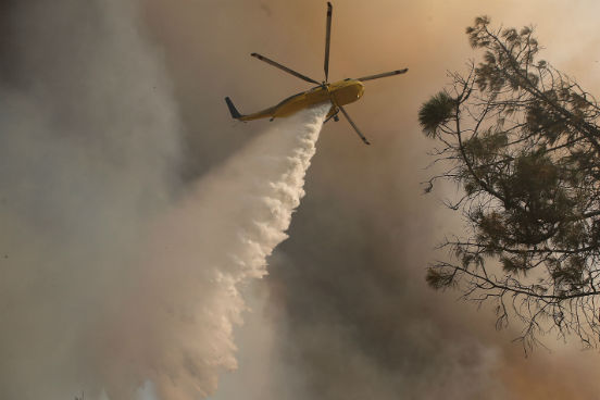 Um helicóptero dos bombeiros é utilizado para jogar água sobre as chamas da região de Lower Lake, na Califórnia. (Imagem: Getty Images) Um helicóptero dos bombeiros é utilizado para jogar água sobre as chamas da região de Lower Lake, na Califórnia. (Imagem: Getty Images)