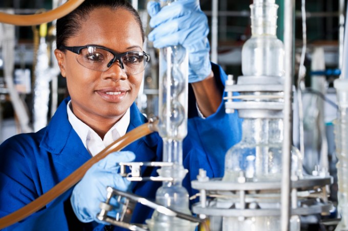 Química trabalhando em equipamento industrial