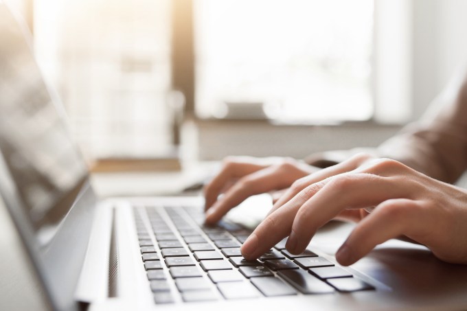 Typing on laptop closeup, chatting in Facebook