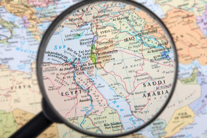 A magnifier zooming in Middle East countries on a global map