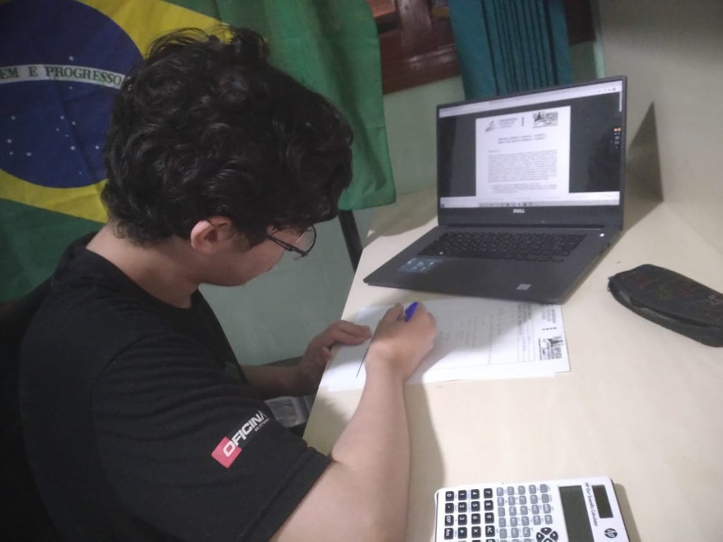 Eduardo em frente à sua mesa, com o computador aberto, estudando para uma das etapas da OLAA.