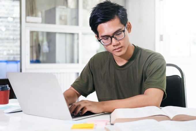 Jovem estudando com livros e computador