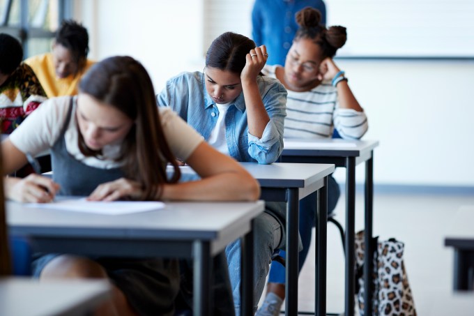 Young multi-ethnic female students writing exams