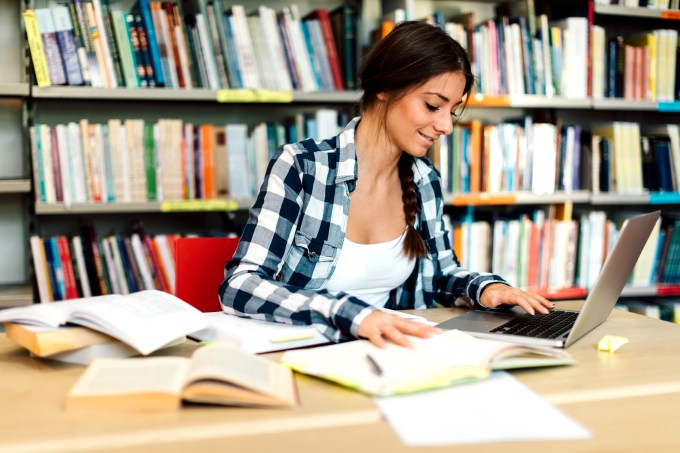 Female student using laptop for taking notes to study