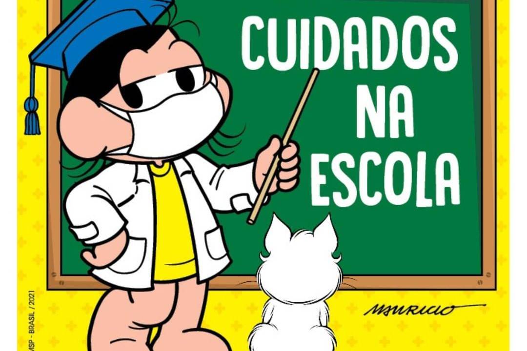 Mônica com avental de professora, com um capelo na cabeça, aponta para a lousa onde está escrito "Cuidados na escola". Também tem um gatinho olhando para a lousa