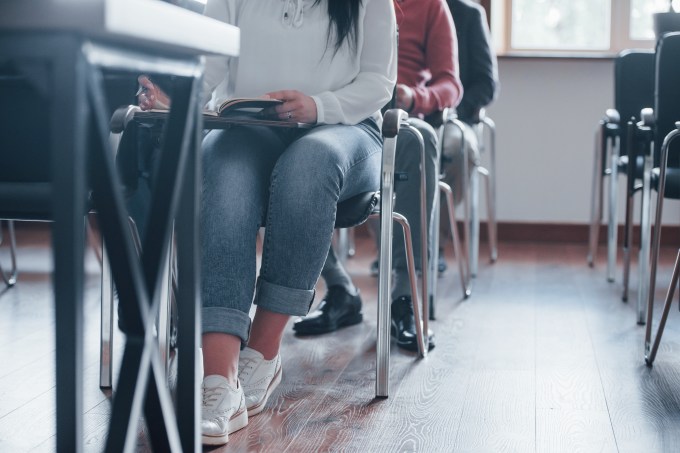 Students seating on the chairs. Group of people at business conference in modern classroom at daytime