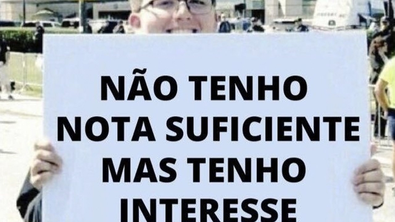 Imagem com rapaz branco, de cabelo castanho, e óculos segurando um cartaz branco escrito com letras pretas: 'Não tenho nota suficiente, mas tenho interesse'.