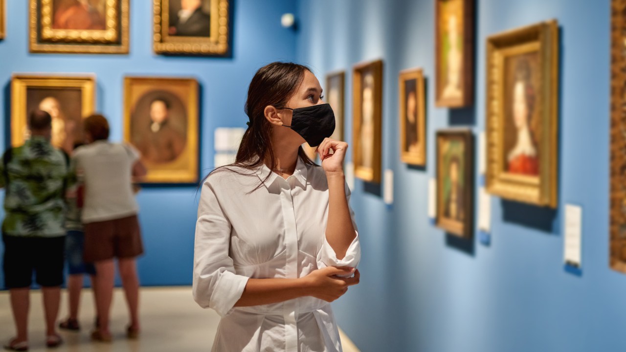 Jovem visita um museu de arte e usa máscara de proteção