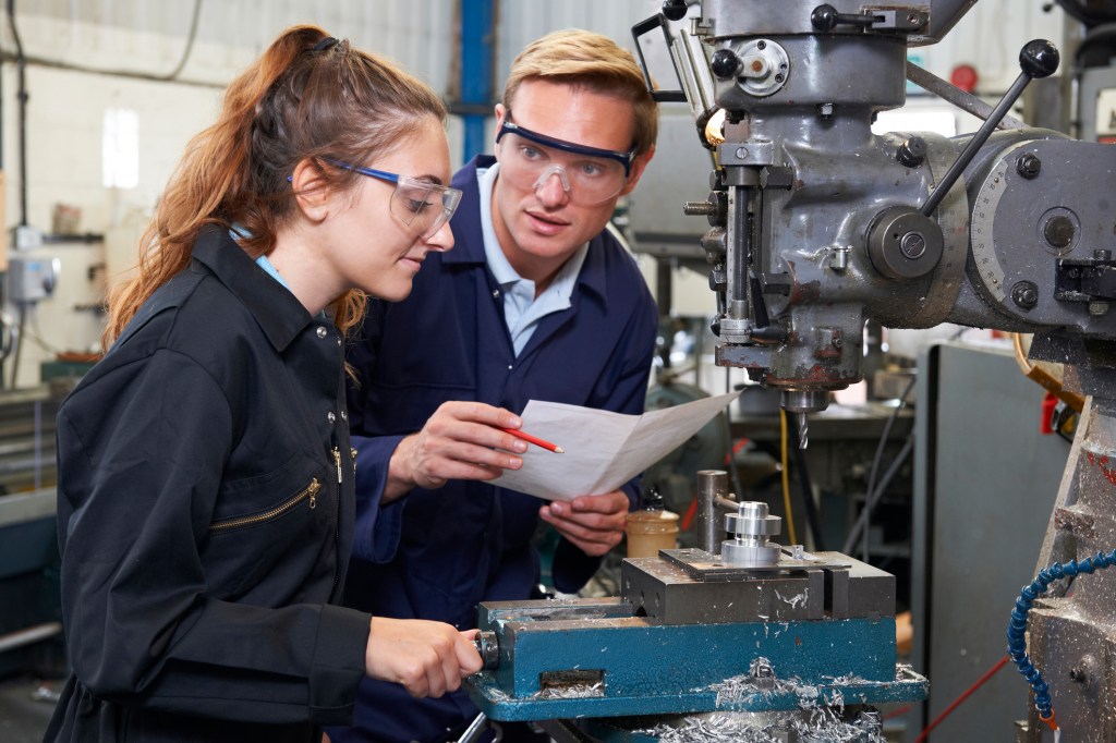 Engenheiro mostrando ao aprendiz como usar o Drill In Factory