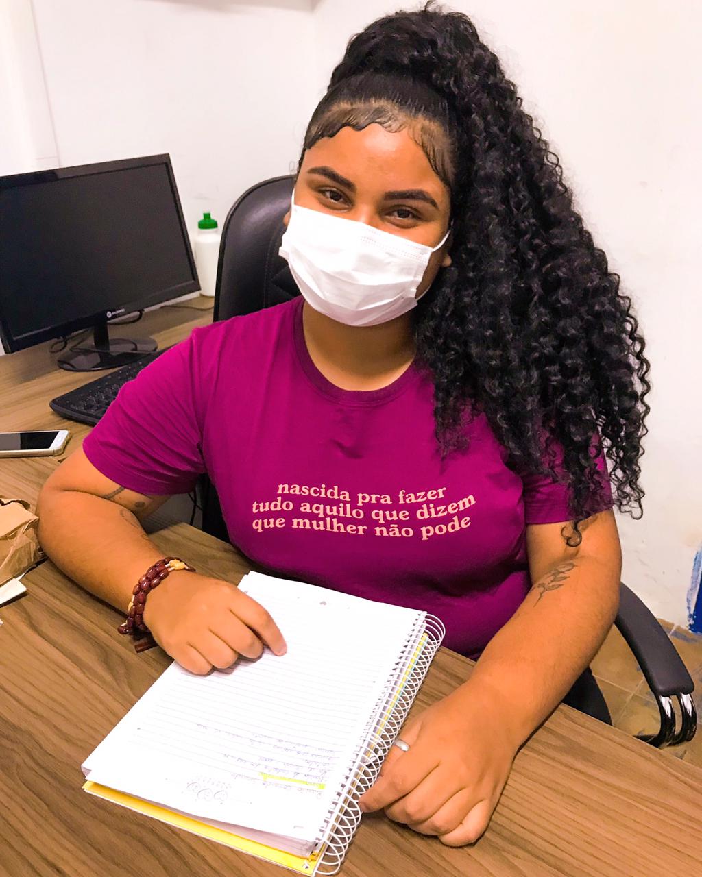 Estudante Jade Beatriz – Enem 2021 Estudante Jade Beatriz usa máscara em uma mesa com computador e um caderno - Enem 2021