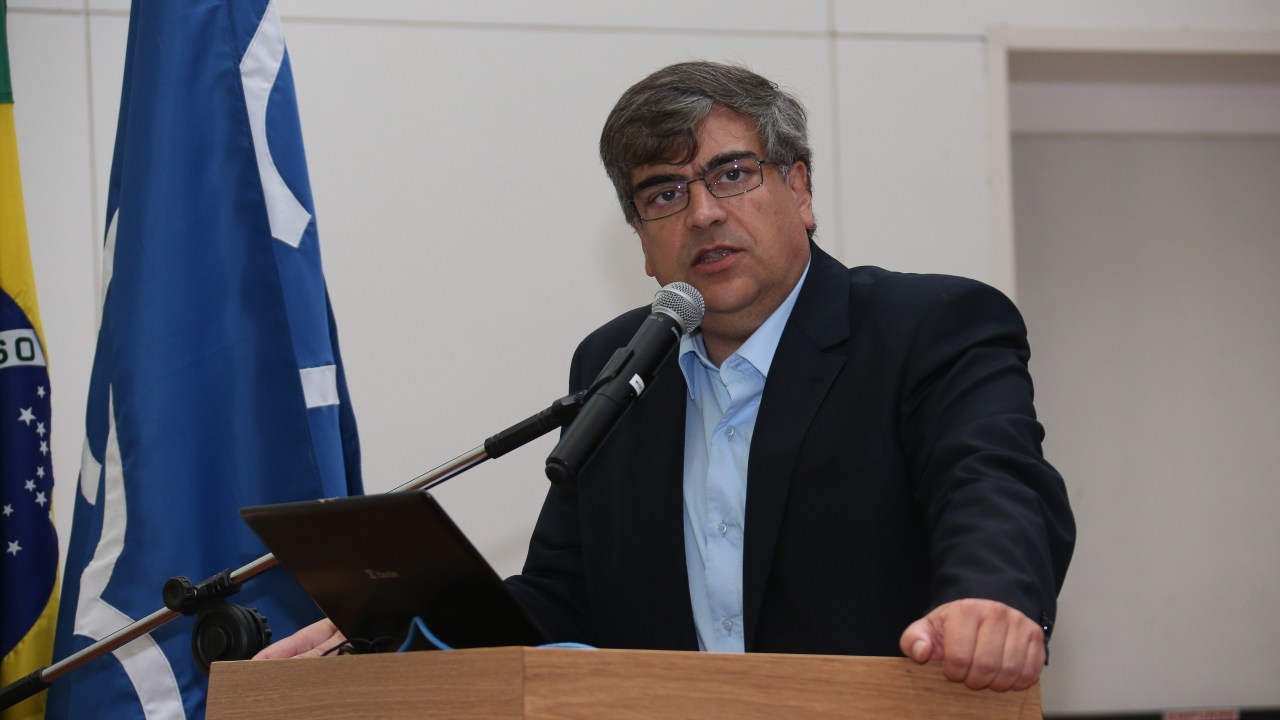 Carlos Gilberto Carlotti Junior em frente a um palanque, durante discurso.