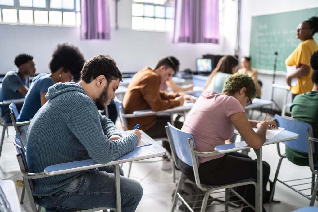 Estudantes sentados em carteiras na sala de aula