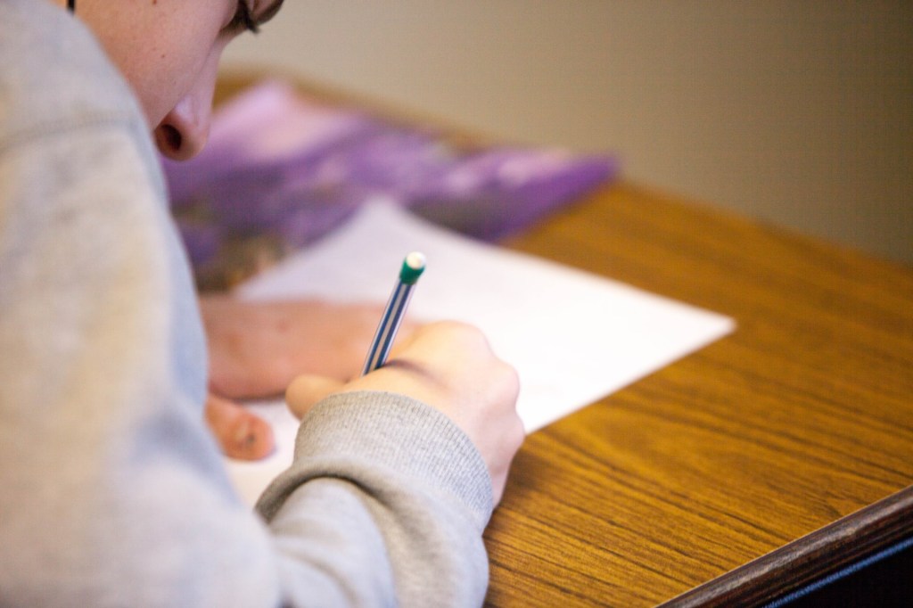 Mulher estudando escrevendo redação à mão no caderno