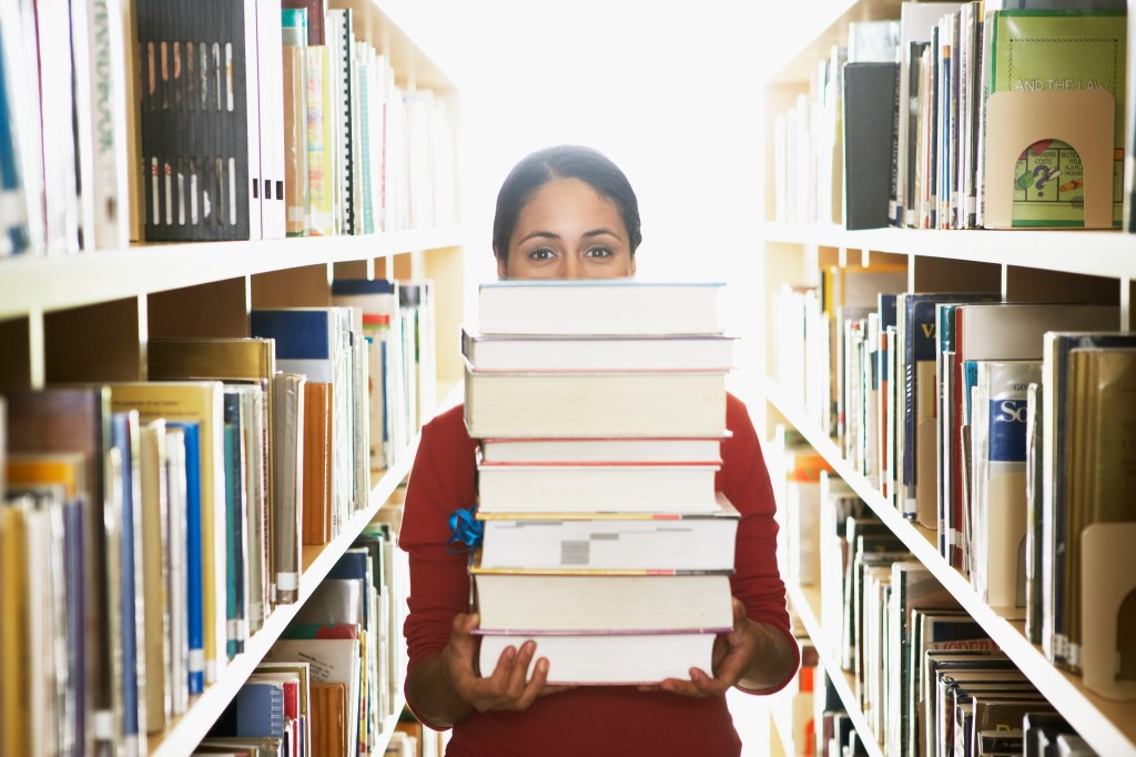 mulher com livros; biblioteca; revisão