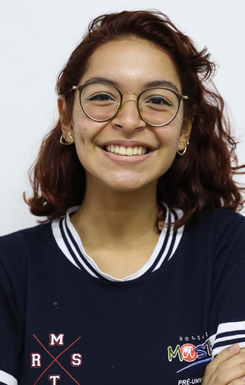 Ana-Alice-Texeira-Freire Ana Alice Teixeira Freire é uma mulher de 17 anos. Tem cabelos castanhos ondulados, usa óculos de grau e está com o uniforme do colégio. Ela sorri para a câmera.