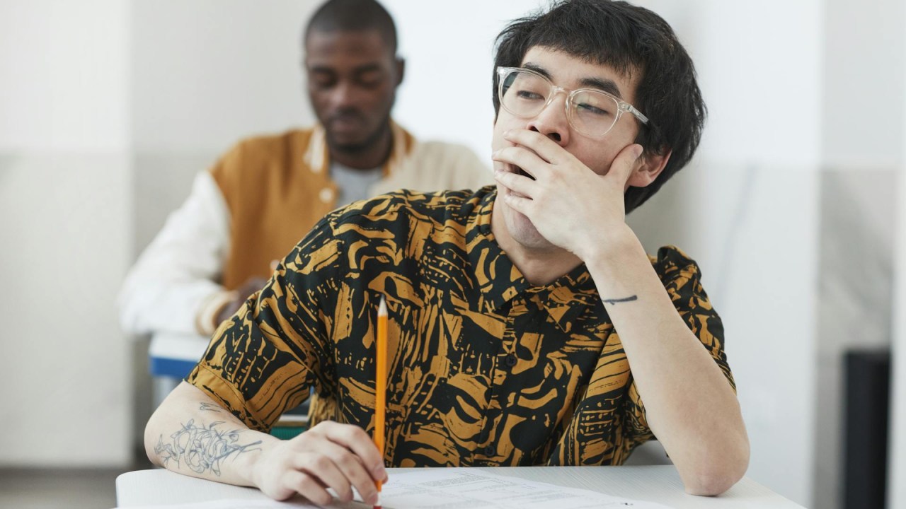 estudante bocejando na sala de aula