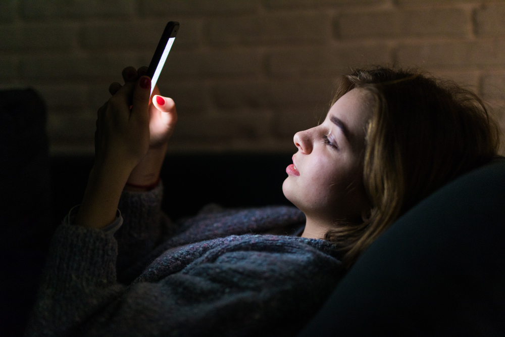 celular mulher mexendo no celular deitada em sofá, no escuro