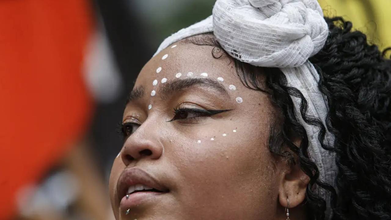 Mulher negra jovem com pintura facial e lenço na cabeça