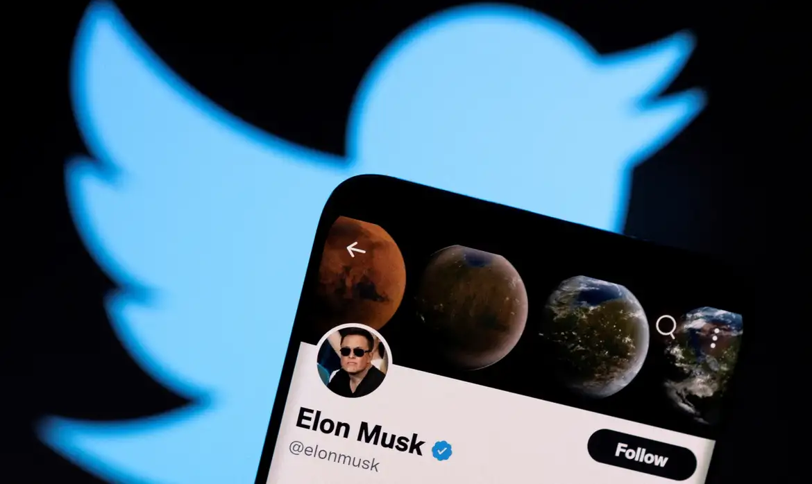 Mão segura celular com perfil de Elon Musk no X