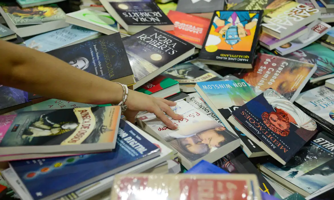 Mão mexe em pilha de livros